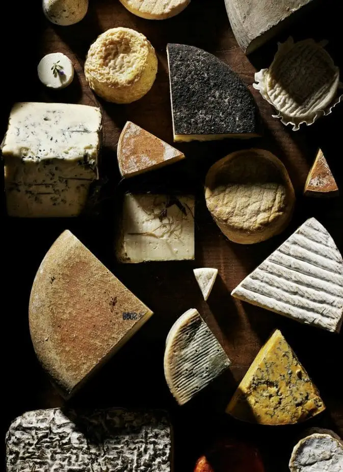 An overhead view of a diverse artisanal cheese selection, showcasing various types, shapes, and textures.