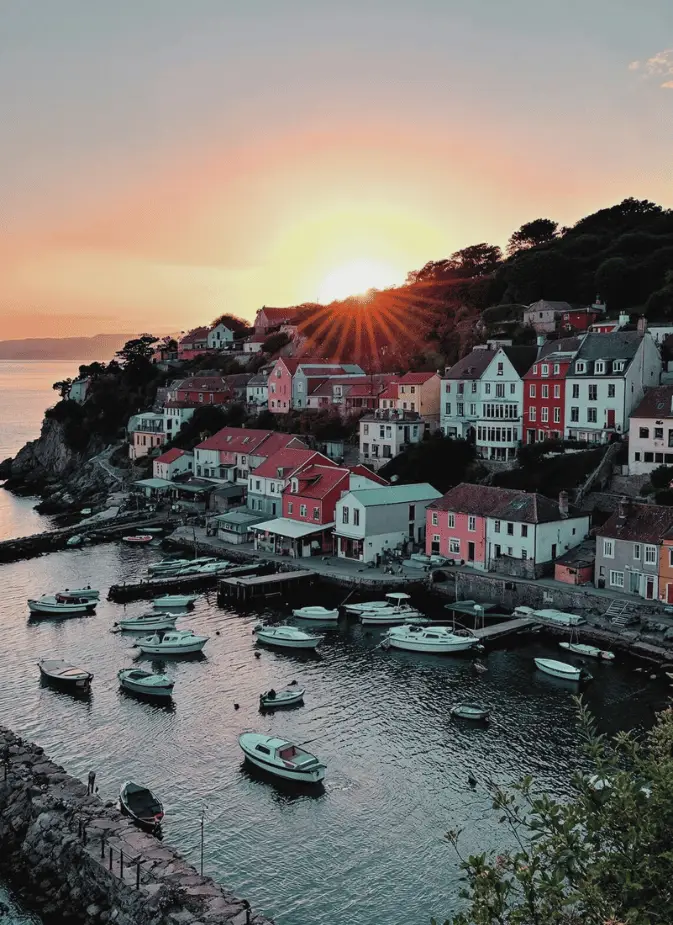 A picturesque coastal town with colorful houses and numerous boats in the harbor, illuminated by a beautiful sunset.